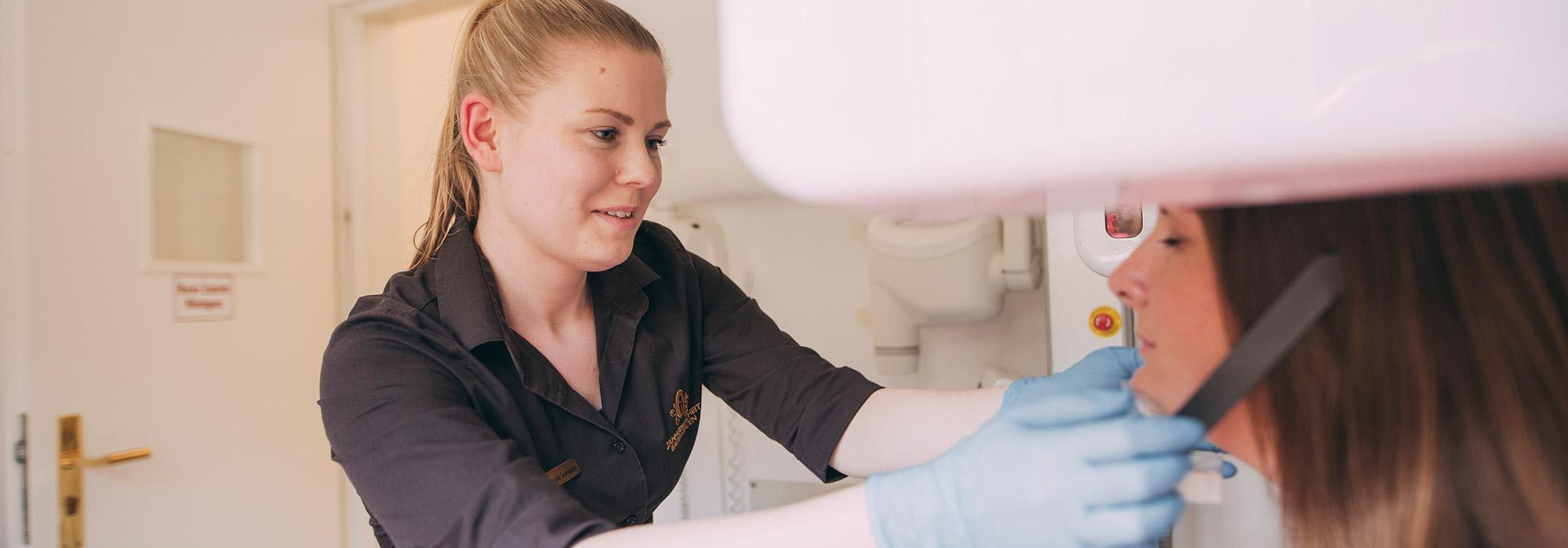 Mitarbeiterin beim Zahnarzt in Baden-Baden bereitet Röntgenaufnahme vor Implantation vor.
