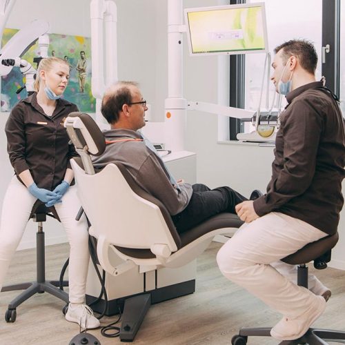 Dr. Andreas Euchner und Mitarbeiterin mit Patient beim Zahnarzt in Baden-Baden.
