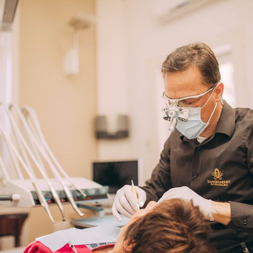Dr. Torsten Kamm bekommt Einblick mit Lupenbrille bei der Parodontosebehandlung in Baden-Baden.